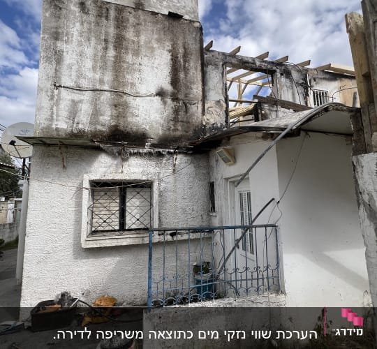 מבנה עם קירות מתקלפים, חלון עם סורגים ודלת כניסה